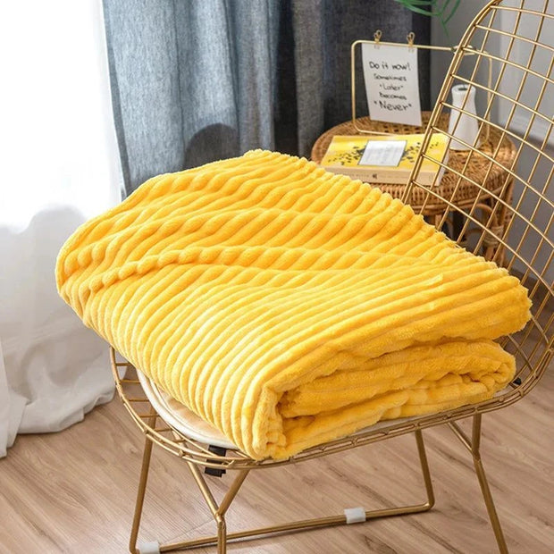 Flannel throw rug blanket in vibrant yellow with thick, wide stripes, displayed on a chair indoors.